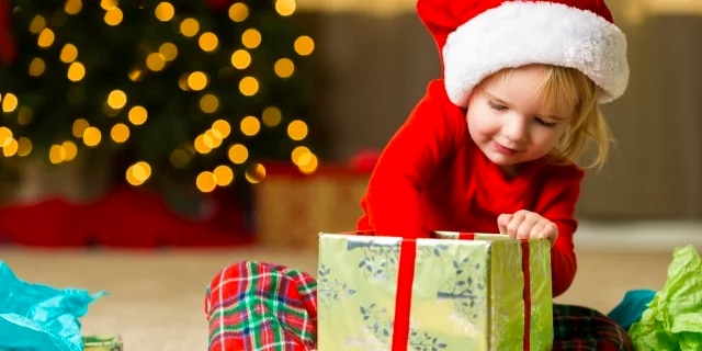 child in santa hat opening a present